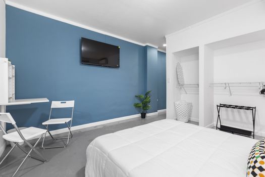 Cozy and modern bedroom with a deep blue accent wall and mounted flat-screen TV.