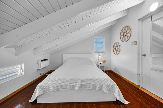 main bedroom with air conditioner, desk, wall art and windows