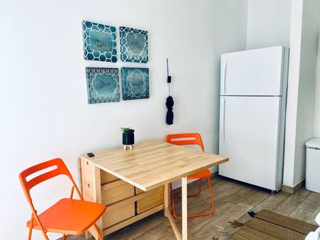 Savor your meals in our charming kitchen area, featuring a convenient fridge, a stylish dining table, and tasteful wall art to enhance your culinary experience.