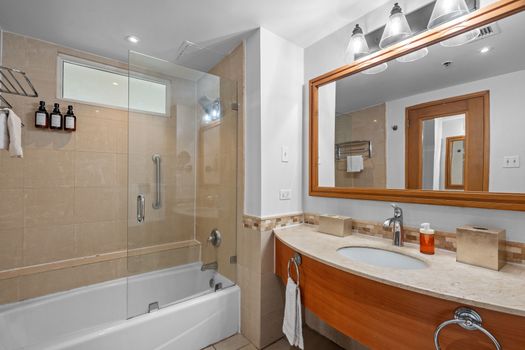 Sparkling clean and modern bathroom featuring a refreshing shower-tub combo, perfect for unwinding after a day of exploring