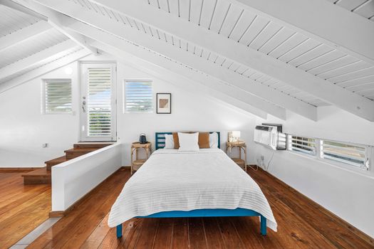 bedroom with bed and private balcony, air condiotioner, wall art and night table