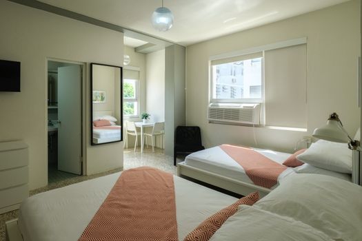 Discover comfort and space in this bright bedroom, featuring a plush bed and a full-length mirror, perfect for getting ready to explore the city or a last-minute check before heading out.