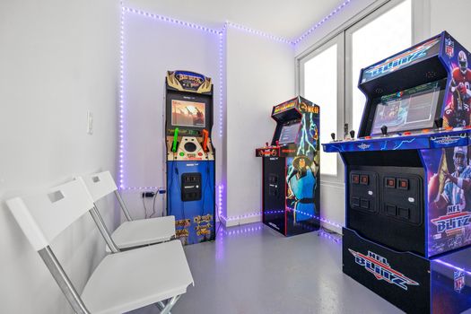 Unleash your inner gamer in this stylish room, adorned with iconic arcade machines and illuminated by enchanting LED lights.