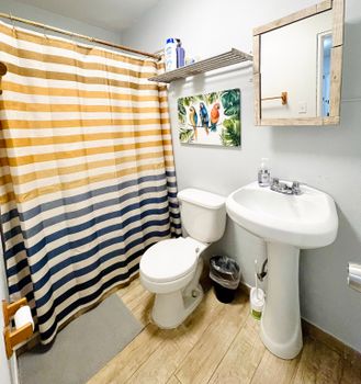 Refresh and rejuvenate! Our clean and modern bathroom features a spacious shower with a fun, striped curtain, ensuring a bright start to your day.