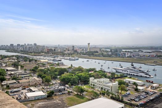 Elevated view of a vibrant waterfront district, where a fleet of boats and yachts rest in the embrace of the city's skyline, all under the watchful eye of a gentle sky