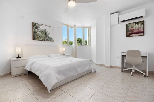 Spacious, sunlit bedroom with comfy bed, AC, and dedicated workspace.