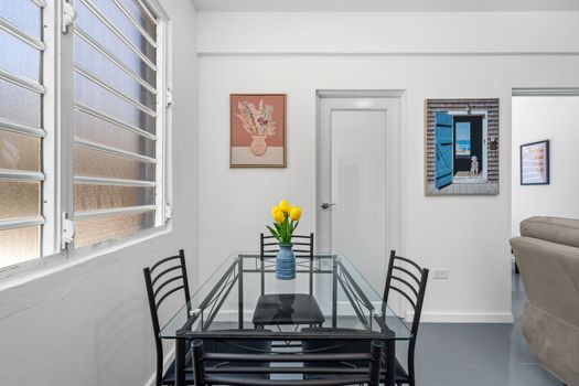 Dine in style in this bright and airy room with a glass table, black chairs, and various artworks on the walls.