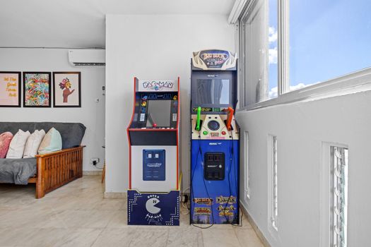 The inviting living space bathes in natural light, complete with an arcade game for endless entertainment.