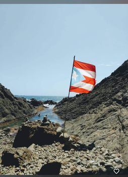 Experience the spirit of Puerto Rico! The vibrant flag proudly flies over a unique rocky cove, leading to refreshing ocean waters.