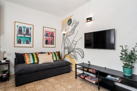 Entertainment Hub: Relax and enjoy your favorite shows on the wall-mounted flat-screen TV in our comfortable living area, complete with a cozy sofa and artistic touches.