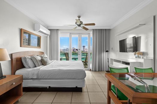 Comfortable studio bedroom with a ceiling fan, TV, and direct access to stunning views.