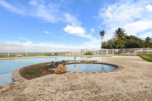 Tome el sol junto a nuestra serena piscina, rodeada de un exuberante paisaje tropical y una vista del cielo azul claro.