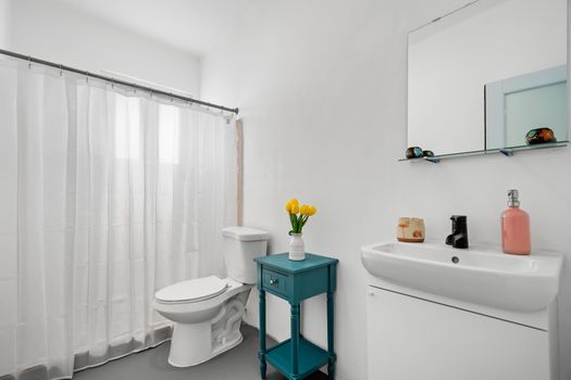 Refresh and rejuvenate in our sleek, white bathroom, complete with a stylish teal accent table and cheerful yellow florals.