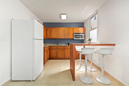 Step into a bright and welcoming kitchen, where the morning sun illuminates a space equipped with modern amenities and a cozy breakfast bar for two.