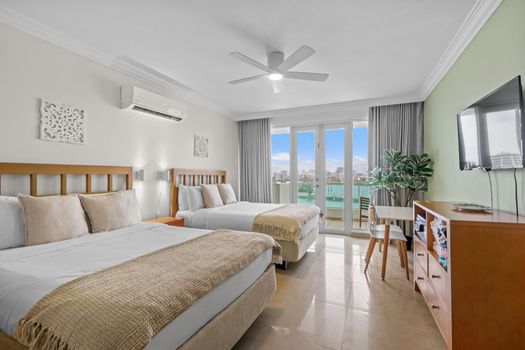 Spacious and inviting bedroom with direct access to a private balcony, offering panoramic water and city vistas.