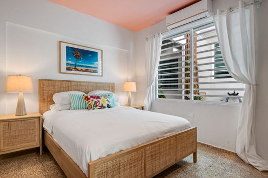 Coastal Comfort: Drift off to sleep surrounded by tasteful design, including a natural wood bed frame and a stunning piece of art that evokes sunny beach days. Perfect for recharging after a day of exploration.