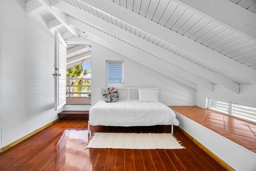 Sunlight & style. This dreamy corner bedroom invites in the breeze with tropical views and cozy vibes.