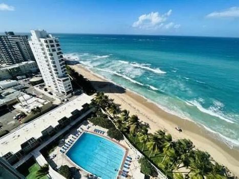 Stunning aerial view of beachfront living—where the turquoise waves meet a sparkling pool oasis.