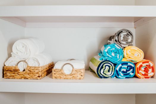 The organized baskets holding freshly rolled white and colorful towels hint at a comforting sense of homeliness.