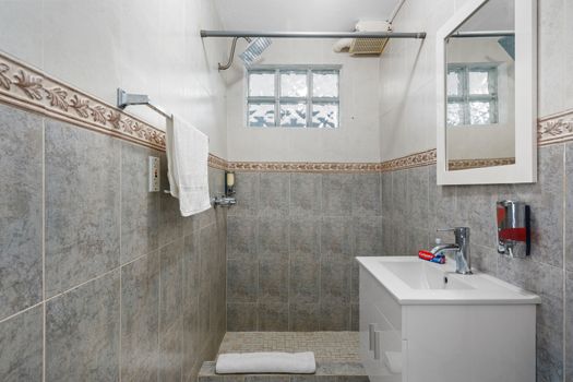 Experience the peaceful ambiance of this modern bathroom sanctuary, showcasing stylish grey tiled walls adorned with intricate patterns.