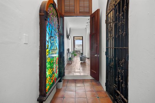 Stroll down the hallway, highlighted by a vibrant stained glass window and an elegant, intricate iron gate.