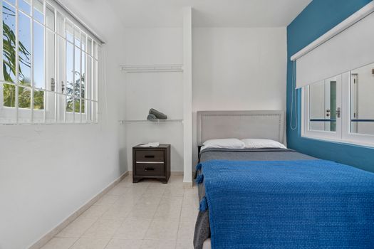 Enjoy revitalizing rest in a roomy bedroom with a lavish bed, modern aesthetics, and an energizing blue accent wall that enhances your well-being.