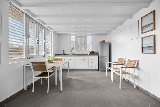 modern kitchen with stainless steel fridge and faucet, dining table and wall art