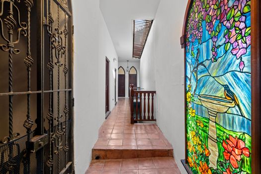 This hallway is the entrance to our home and is filled with natural light and beautiful stained glass windows. The hallway is tiled with terracotta tiles and has a wooden railing.