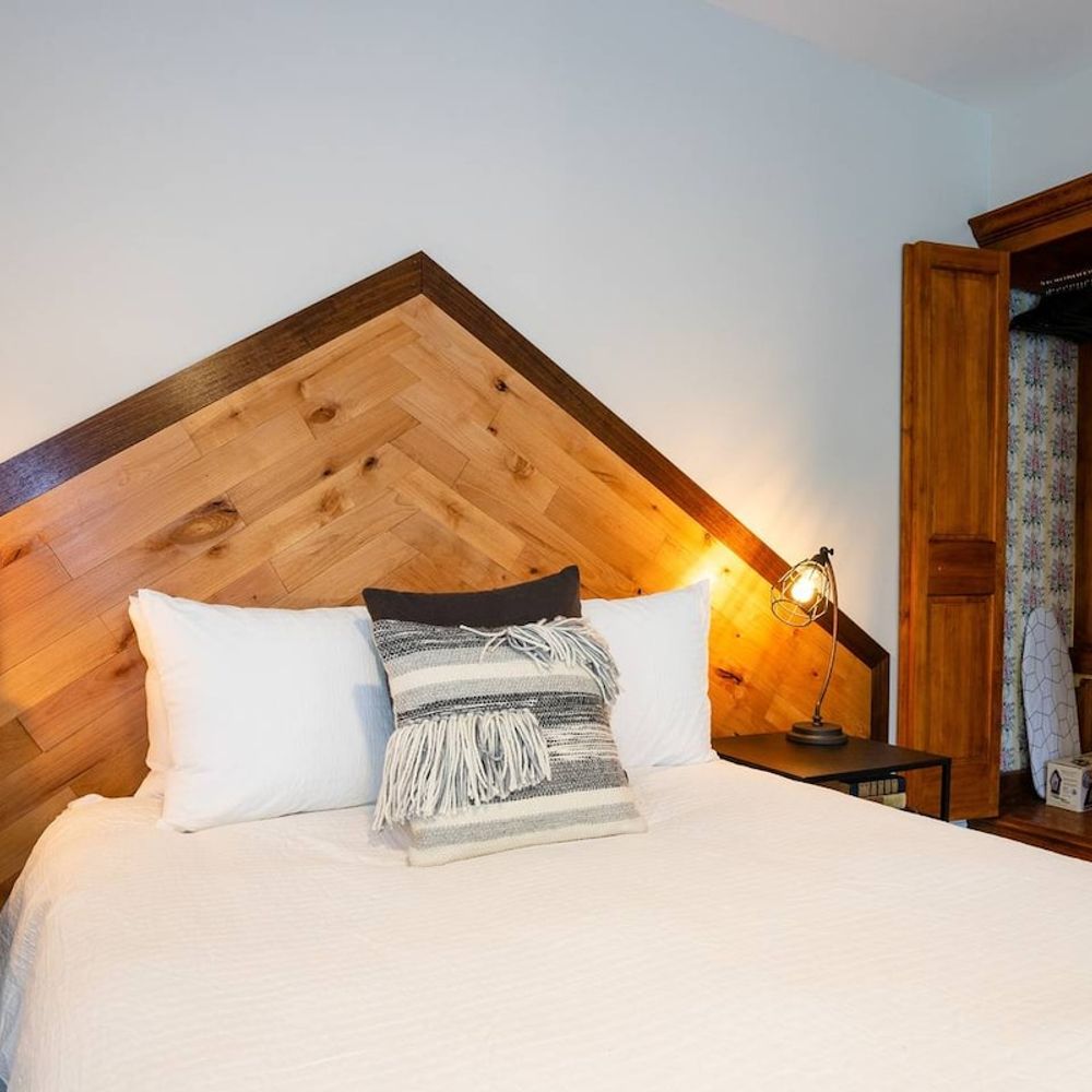 The room includes a wardrobe, as well as an iron + ironing board