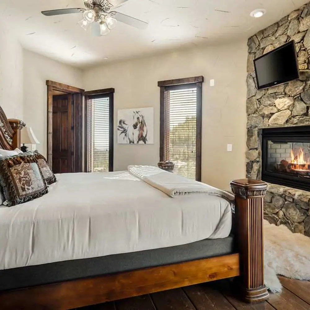 Bedroom 4 with a king bed, a flatscreen TV, a see-through gas fireplace, a balcony exit, and a private full ensuite bathroom