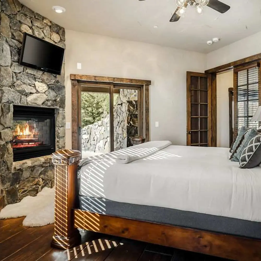 Bedroom 4 with a king bed, a flatscreen TV, a see-through gas fireplace, a balcony exit, and a private full ensuite bathroom