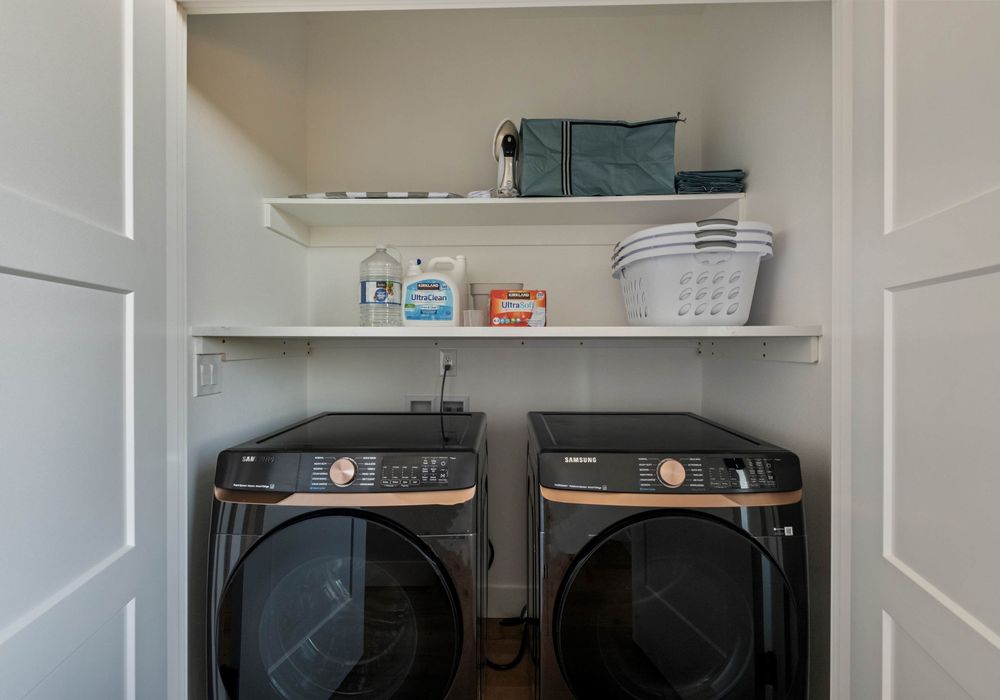 In-unit laundry with detergent, towels, and shelves for guest use.