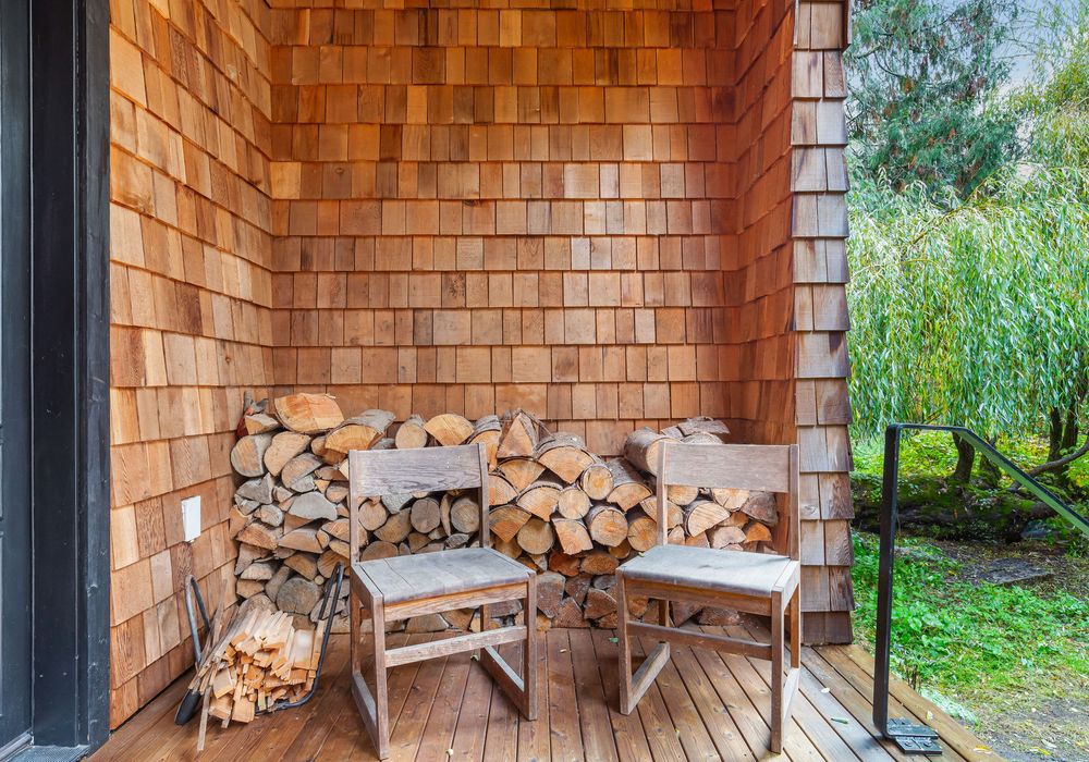 Perfectly stacked firewood and chairs for a welcoming fireplace experience.
