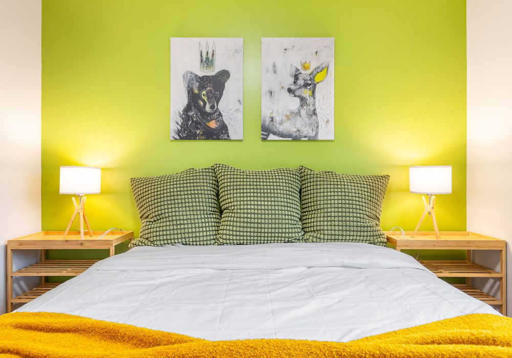 This cozy bedroom boasts lush green walls and a stunning lampshade, creating a peaceful and stylish space.
