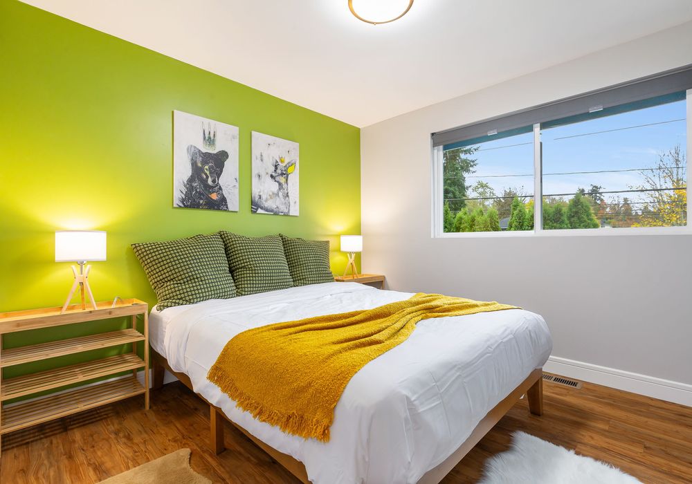 This cozy bedroom boasts lush green walls and a stunning lampshade, creating a peaceful and stylish space.