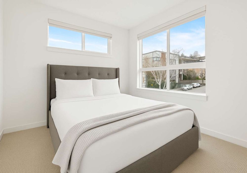 Bright second bedroom with a queen bed and soft carpet. Comfortable and quiet.