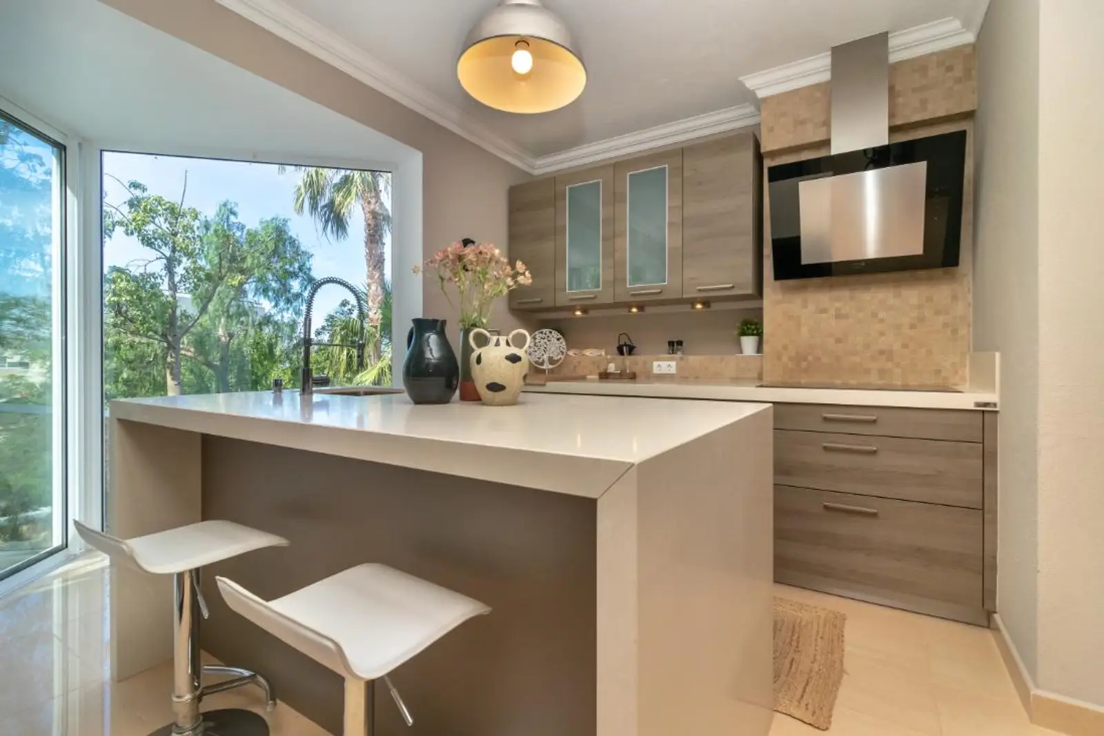 Kitchen with white island and breakfast bar, wood-fronted cabinets and corner window onto garden
