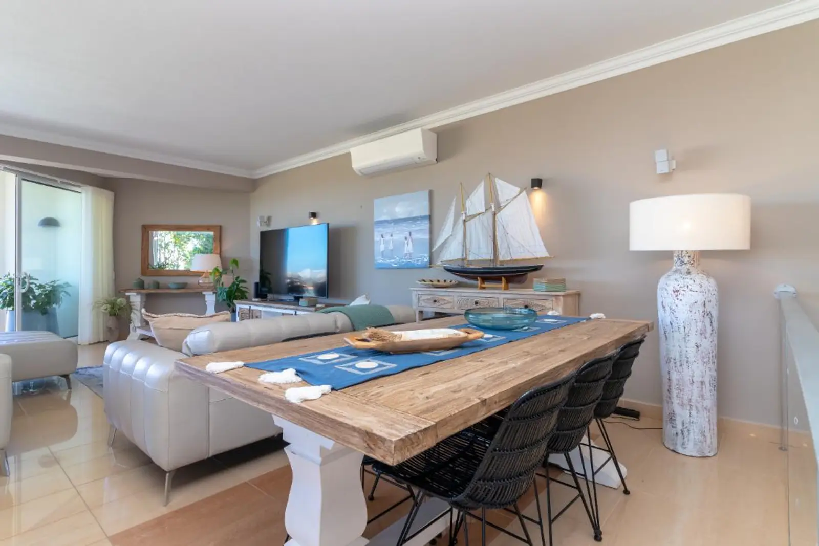 Dining table set for six with the living area and terrace beyond
