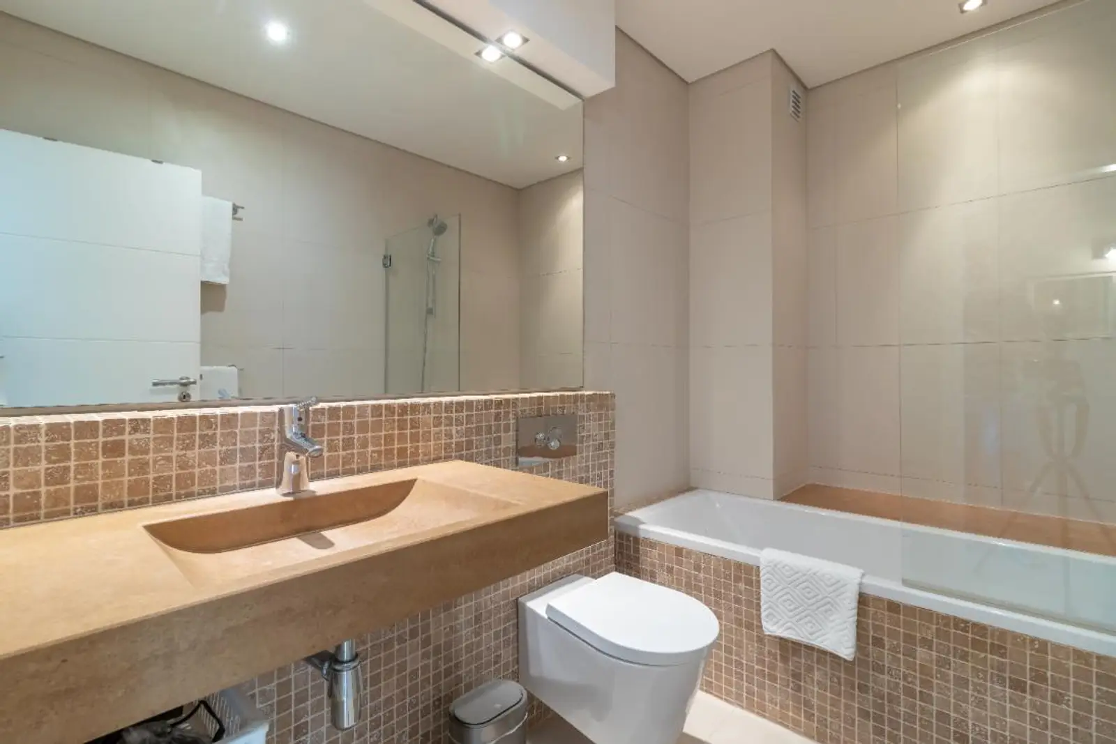 Bathroom in travertine and mosaic tile with stone basin and bath