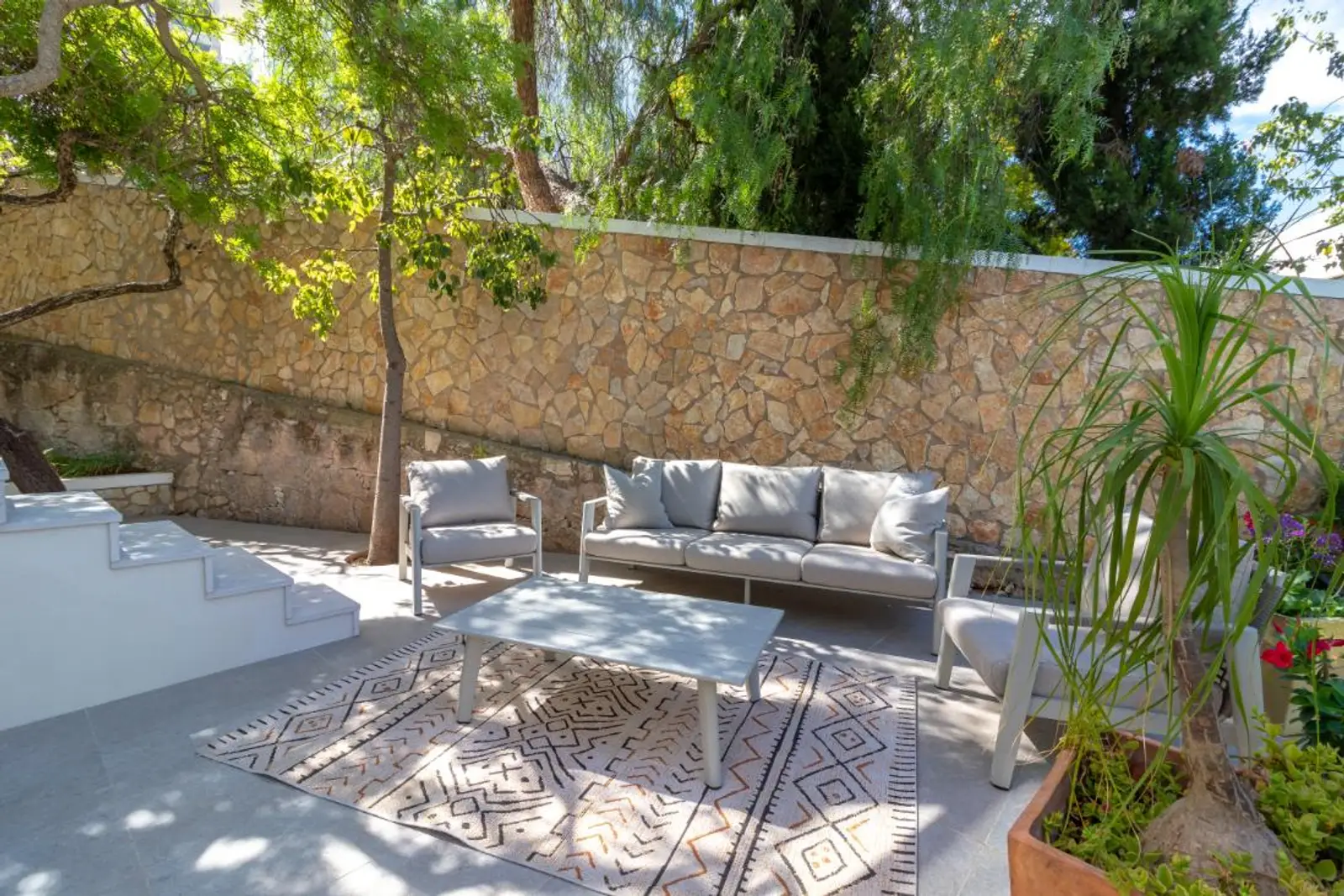 Outdoor sofa and coffee table against the stone garden wall
