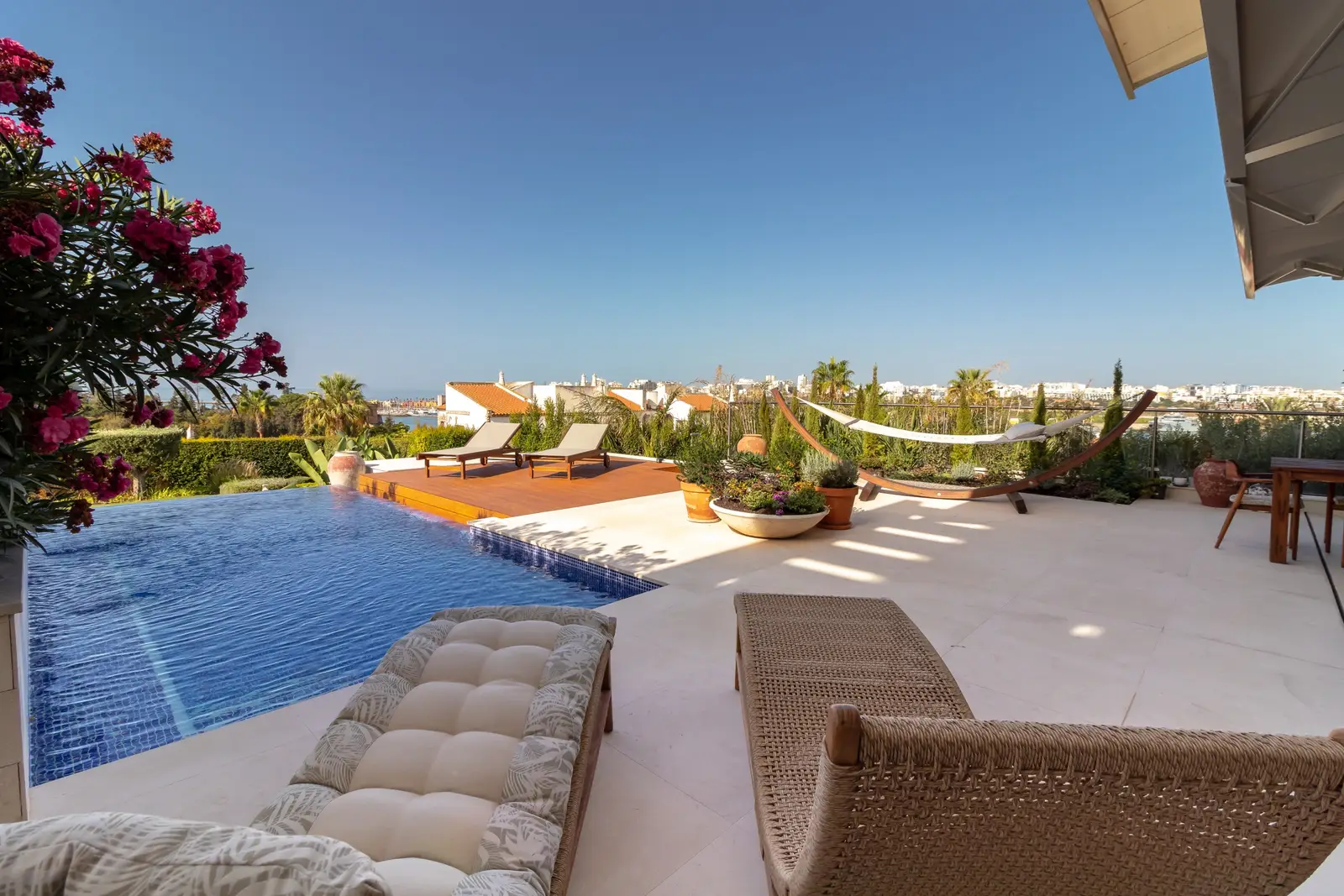 Pool terrace with cushioned loungers, hammock and oleander, looking toward the sea