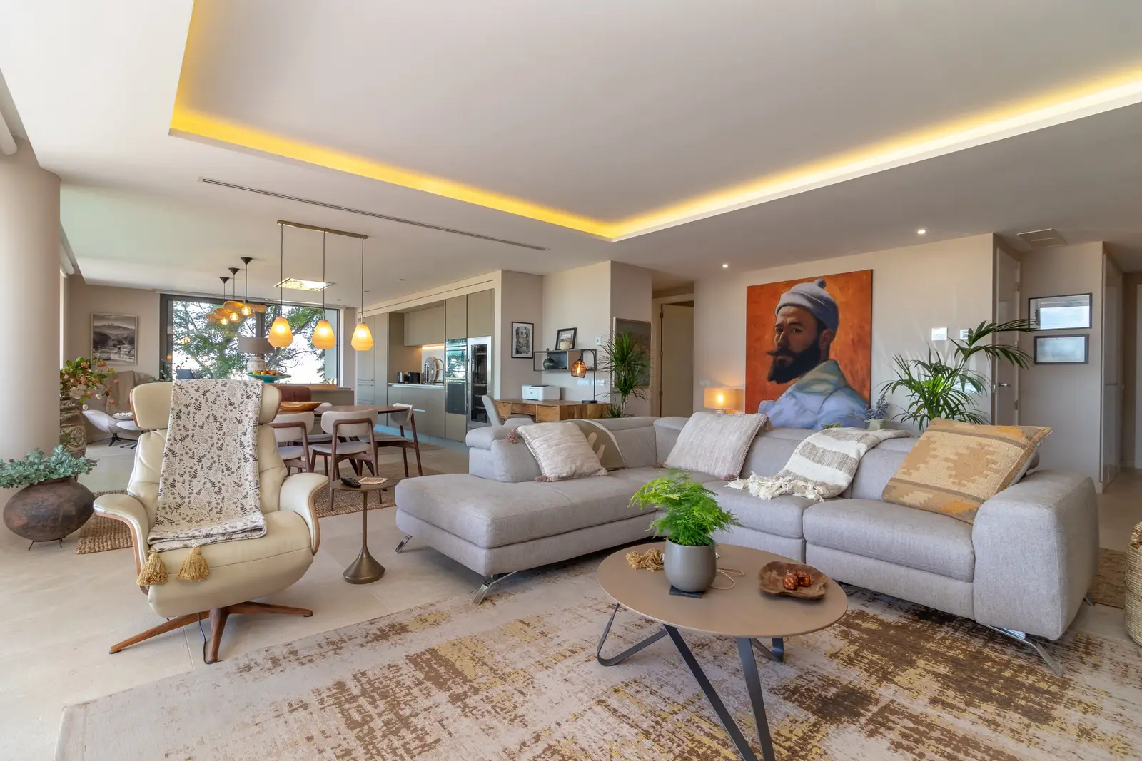 Open-plan living room with corner sofa, oval dining table and kitchen beyond, cove lighting above