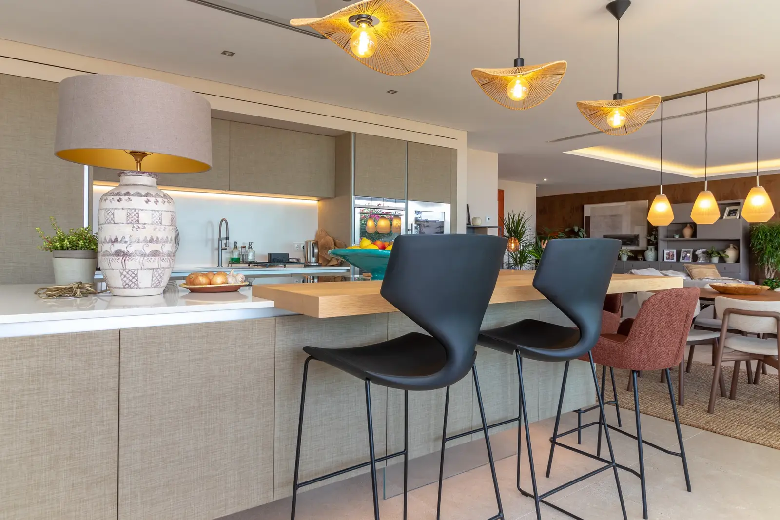 Kitchen counter and breakfast bar with bar stools and pendant lights, dining area beyond