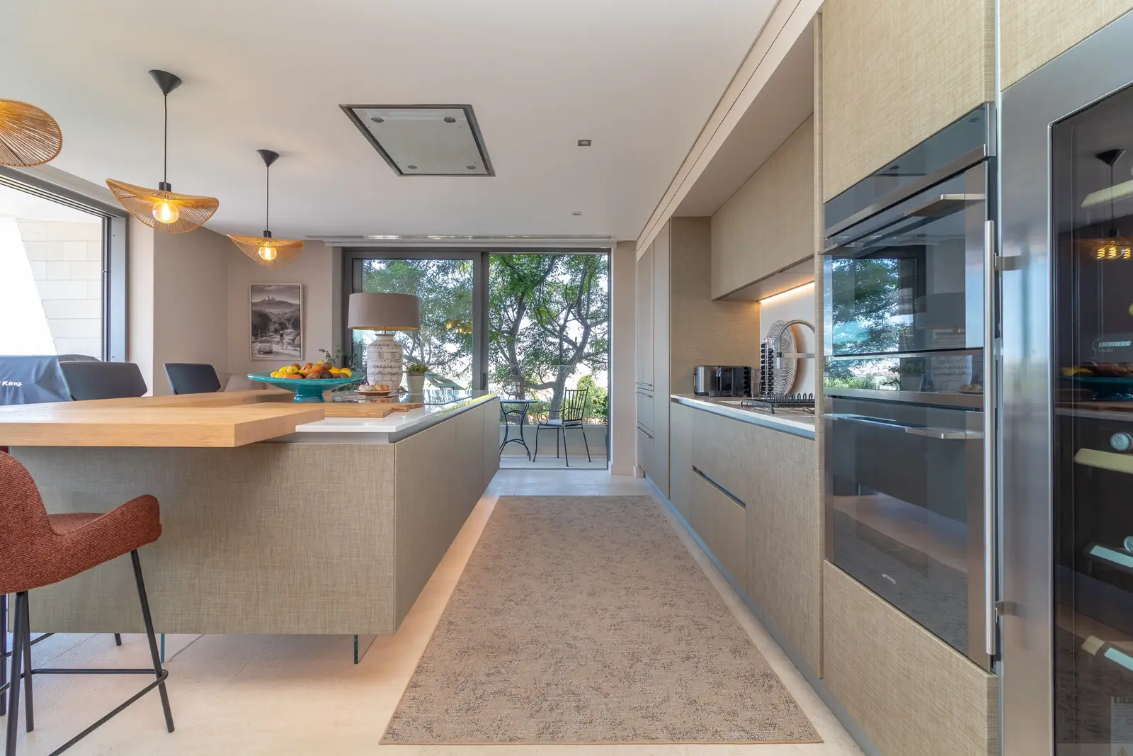 Galley kitchen with integrated ovens, wine cooler and breakfast bar, opening onto the terrace