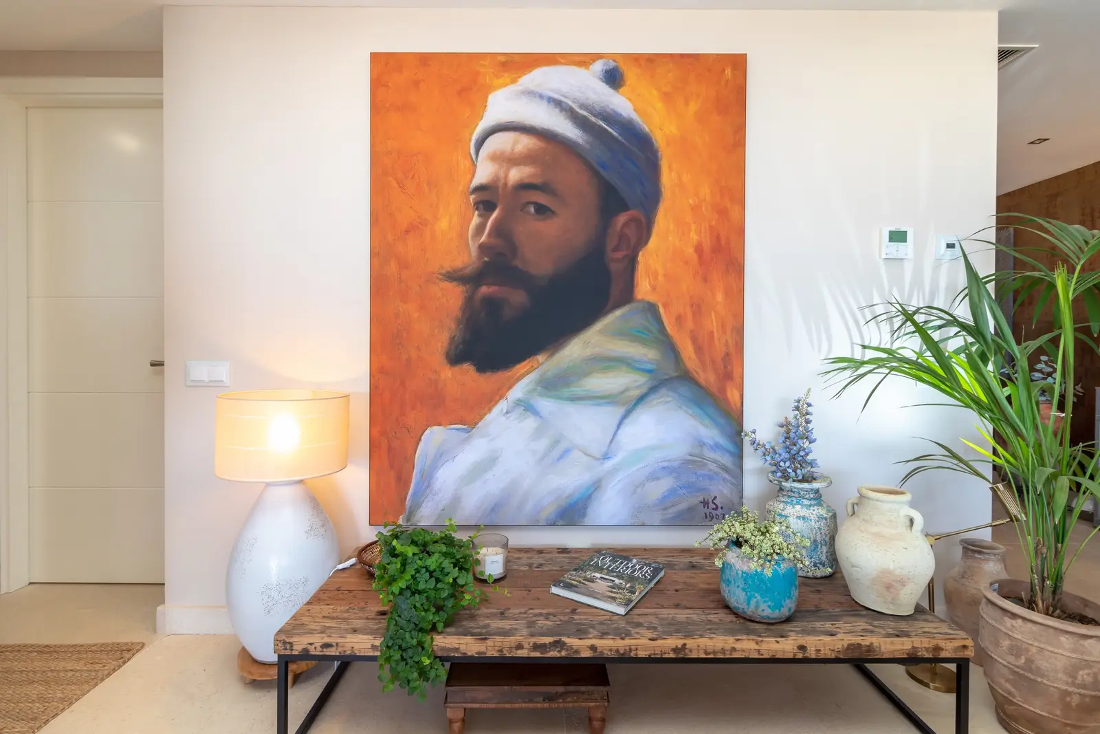 Entrance hall console table with ceramic lamp, plants and a large portrait painting