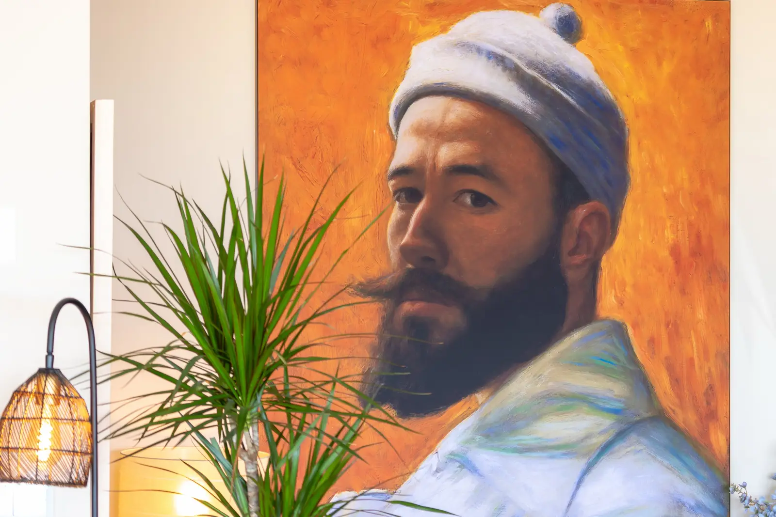 Detail of a large portrait painting beside a potted palm
