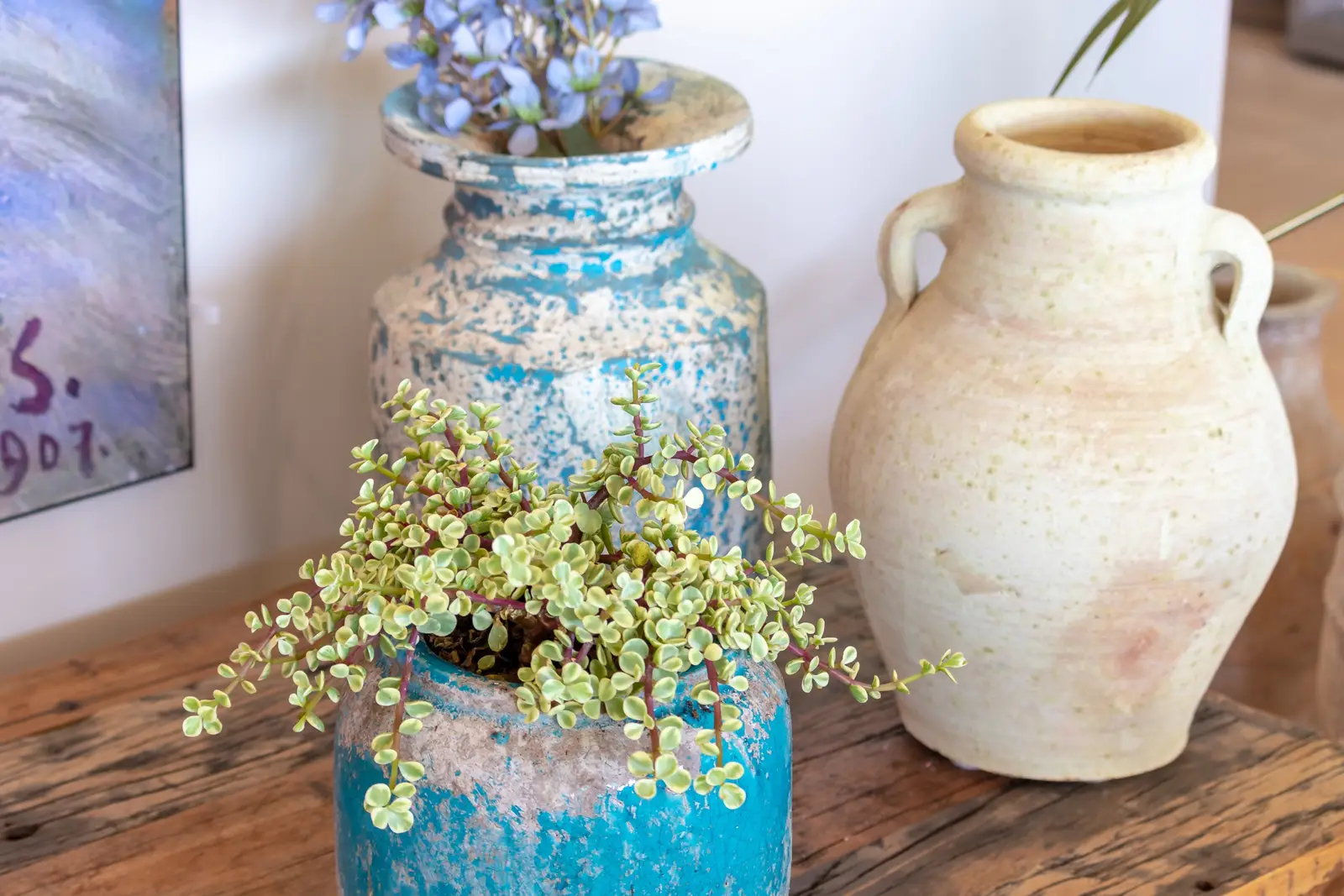 Turquoise and cream ceramic vases on a rustic wooden console