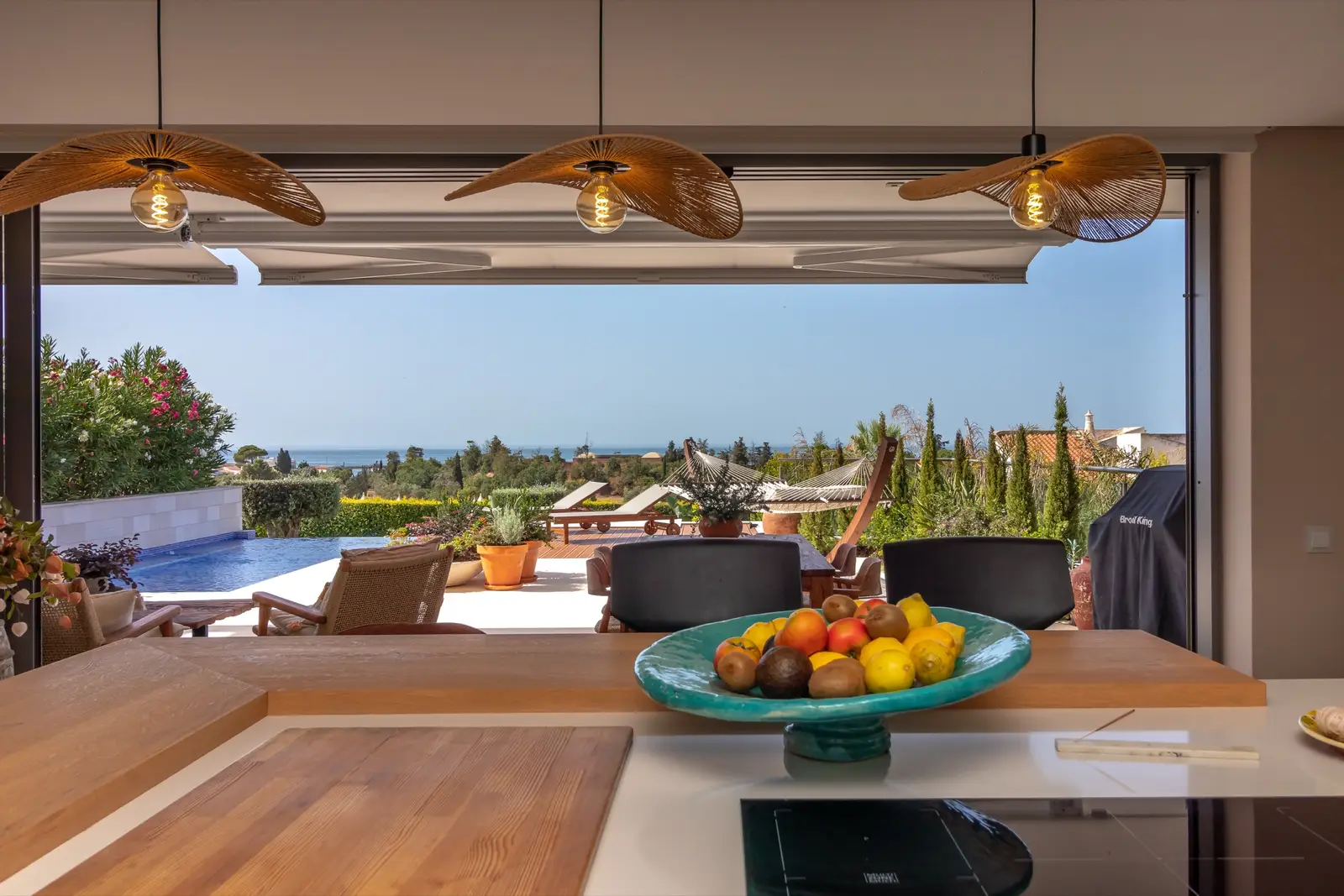 Kitchen counter with fruit bowl and sliding glass walls open to the pool terrace and sea