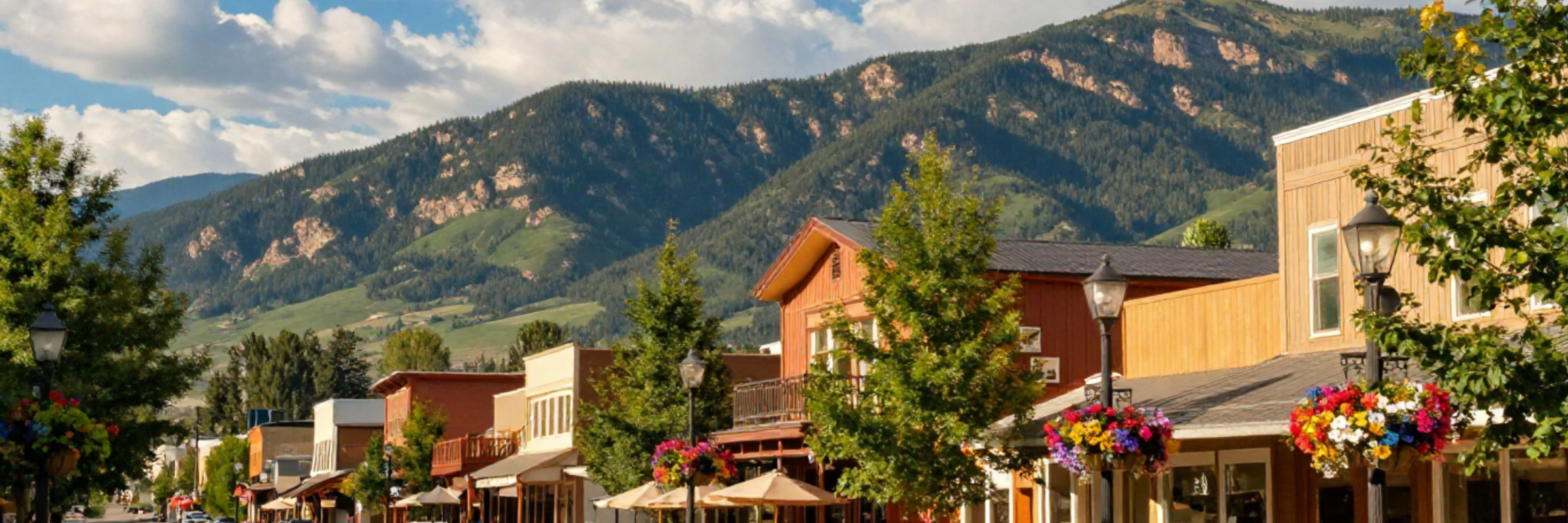 Colorado mountain town main street in summer with outdoor patios, colorful flowers, and scenic mountain views for a relaxing weekend getaway.