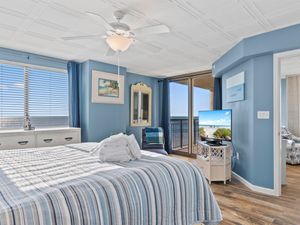 - Oceanfront bedroom with striped bedding and sea views   - Large windows and balcony access for peaceful mornings   - TV and décor create cozy coastal retreat space